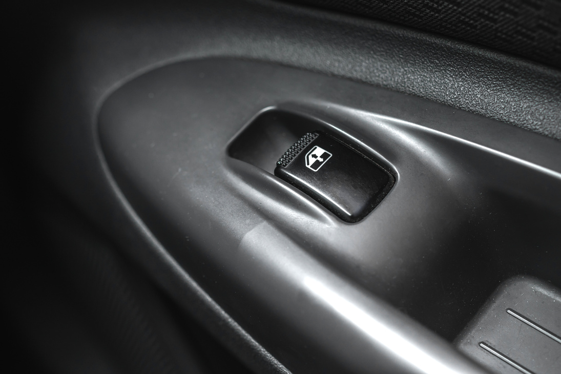 Black car window lifter button in car door close-up background